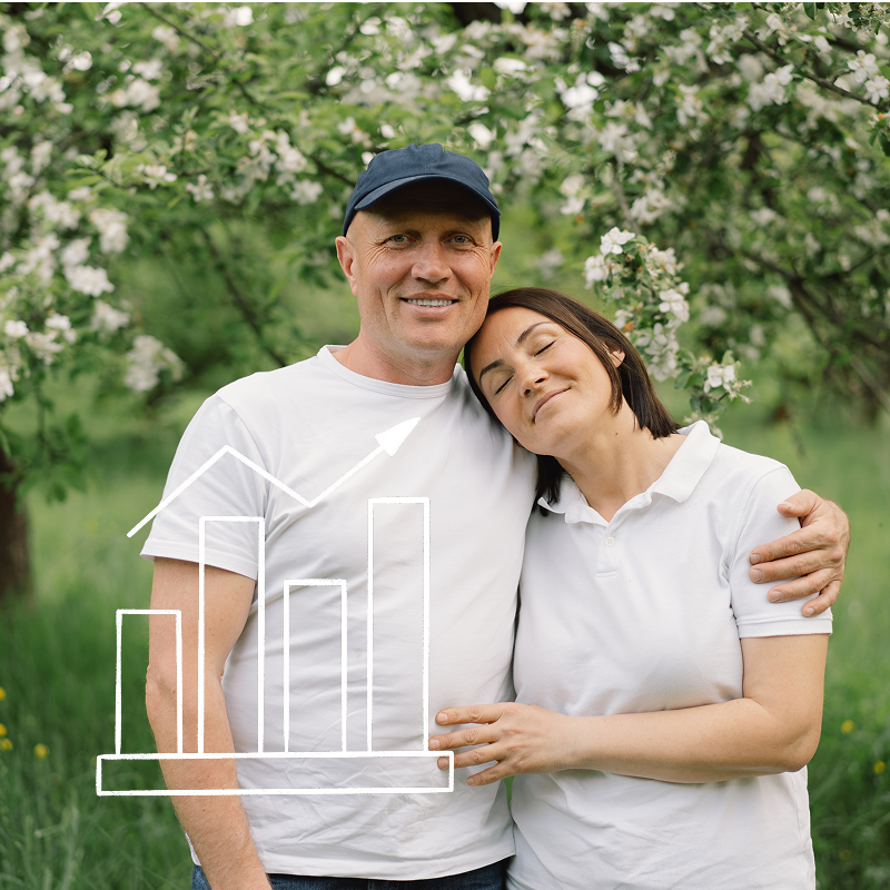 Inimene udustatud näoga hoiab nutitelefoni, istudes laua taga, millel on kollaste lillede vaas; taustal on köögikapid