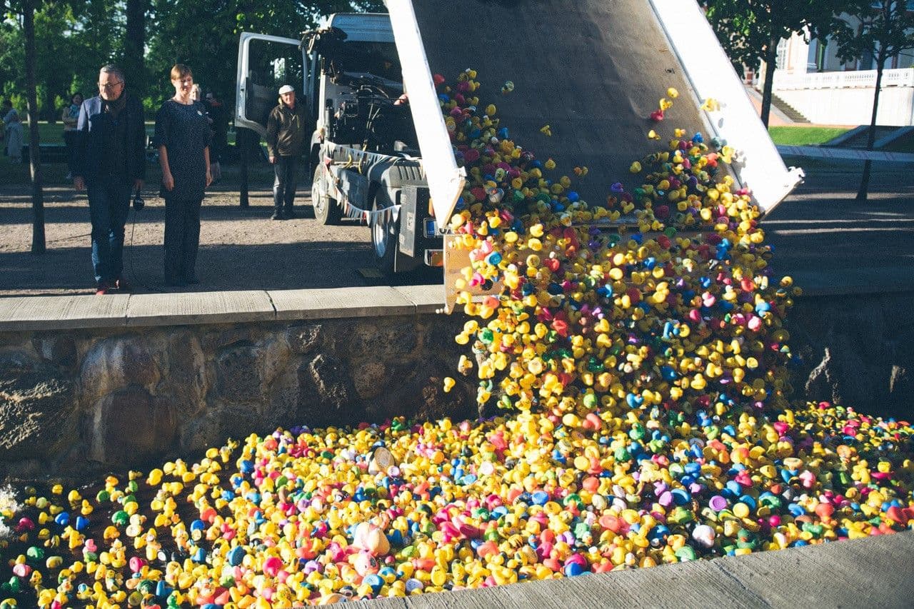 Veoauto kallutab maha suure hulga kummikuid, samal ajal kui kaks inimest seisavad kõrval ja jälgivad toimuvat.