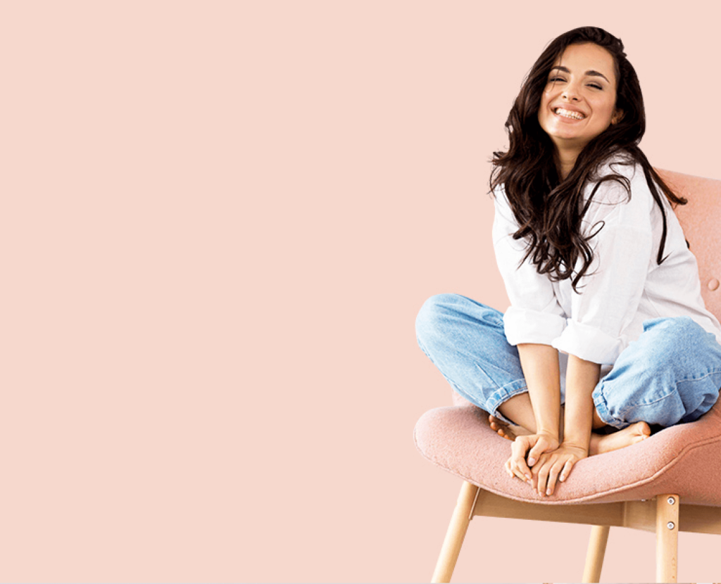 Inimene valgel särgil ja teksades roosal toolil virsikukarva taustal