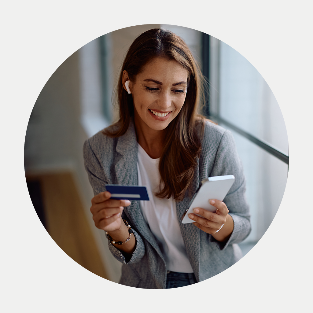 Inimene udustatud näoga hoiab nutitelefoni, istudes laua taga, millel on kollaste lillede vaas; taustal on köögikapid