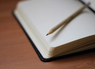 Avatud märkmik tühjade lehtedega ja pliiatsiga puidust pinnal