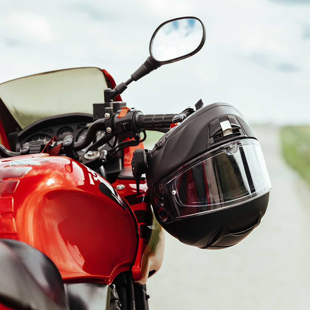 Punane mootorratas musta kiivriga juhtraual, taustal udune väli