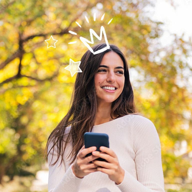 Inimene udustatud näoga hoiab nutitelefoni, istudes laua taga, millel on kollaste lillede vaas; taustal on köögikapid