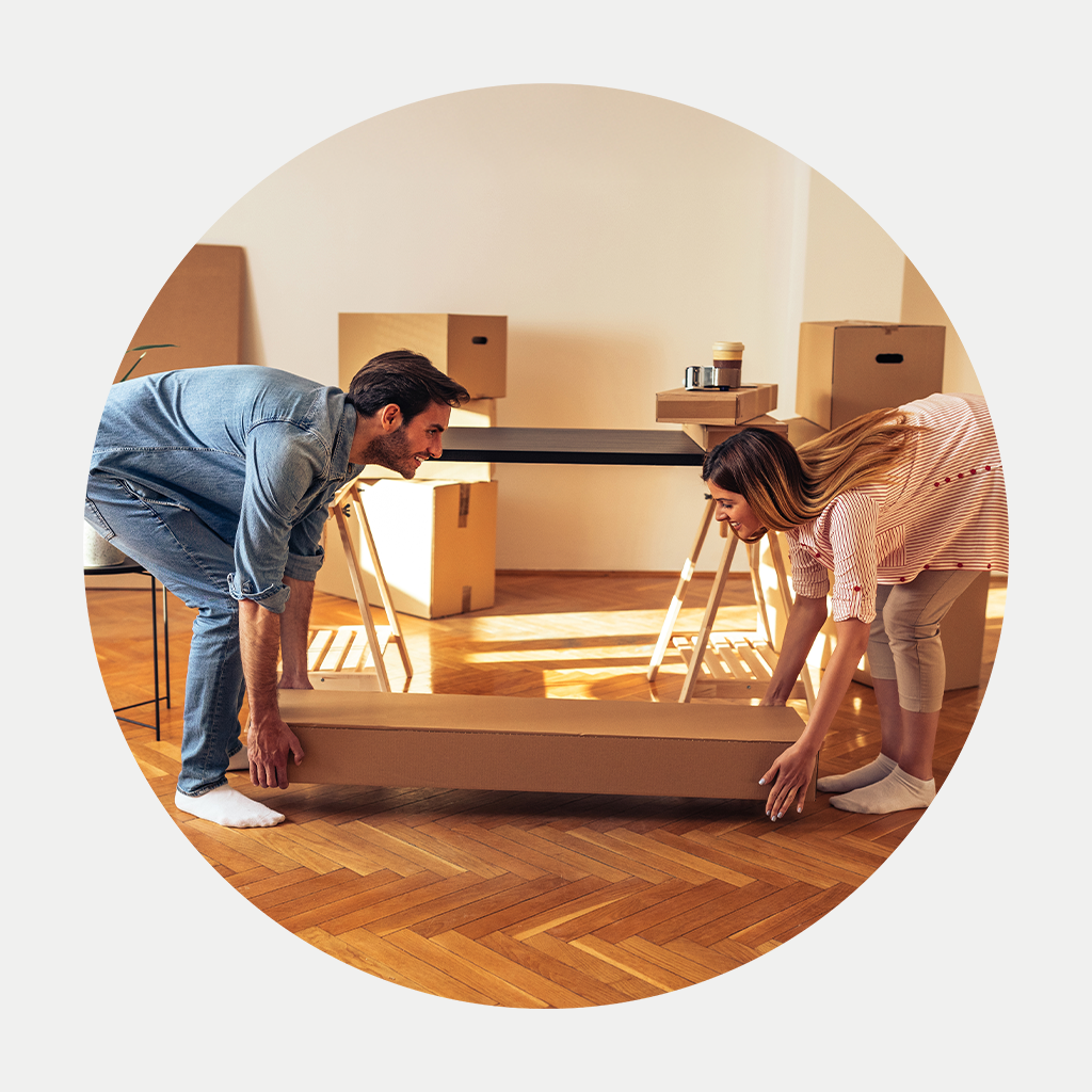 Inimene udustatud näoga hoiab nutitelefoni, istudes laua taga, millel on kollaste lillede vaas; taustal on köögikapid