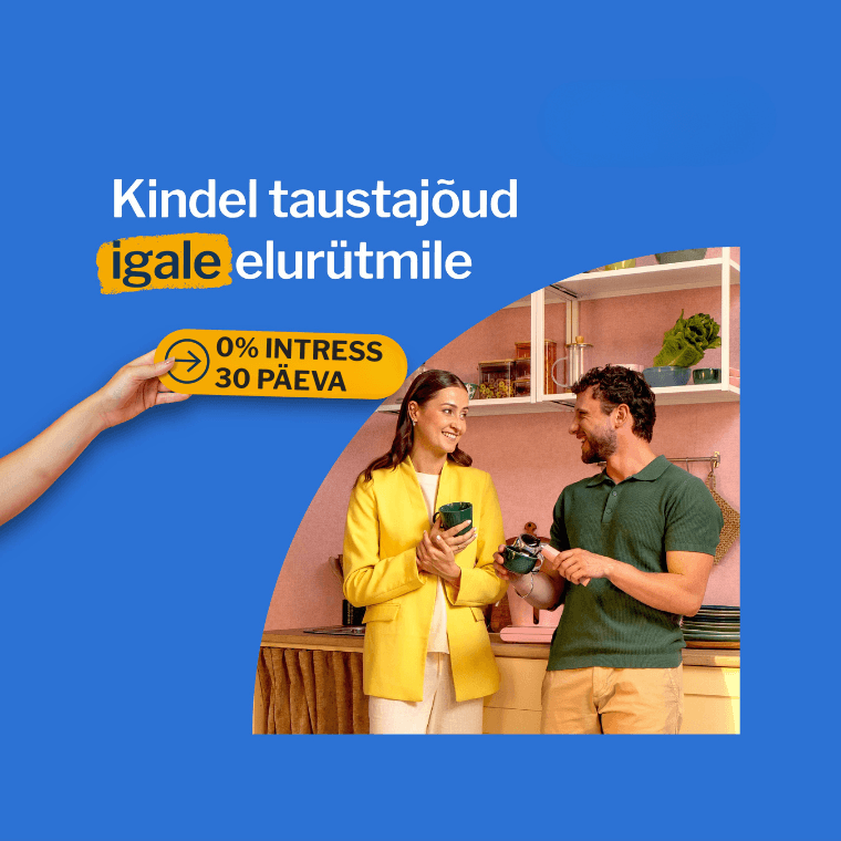 Inimene udustatud näoga hoiab nutitelefoni, istudes laua taga, millel on kollaste lillede vaas; taustal on köögikapid