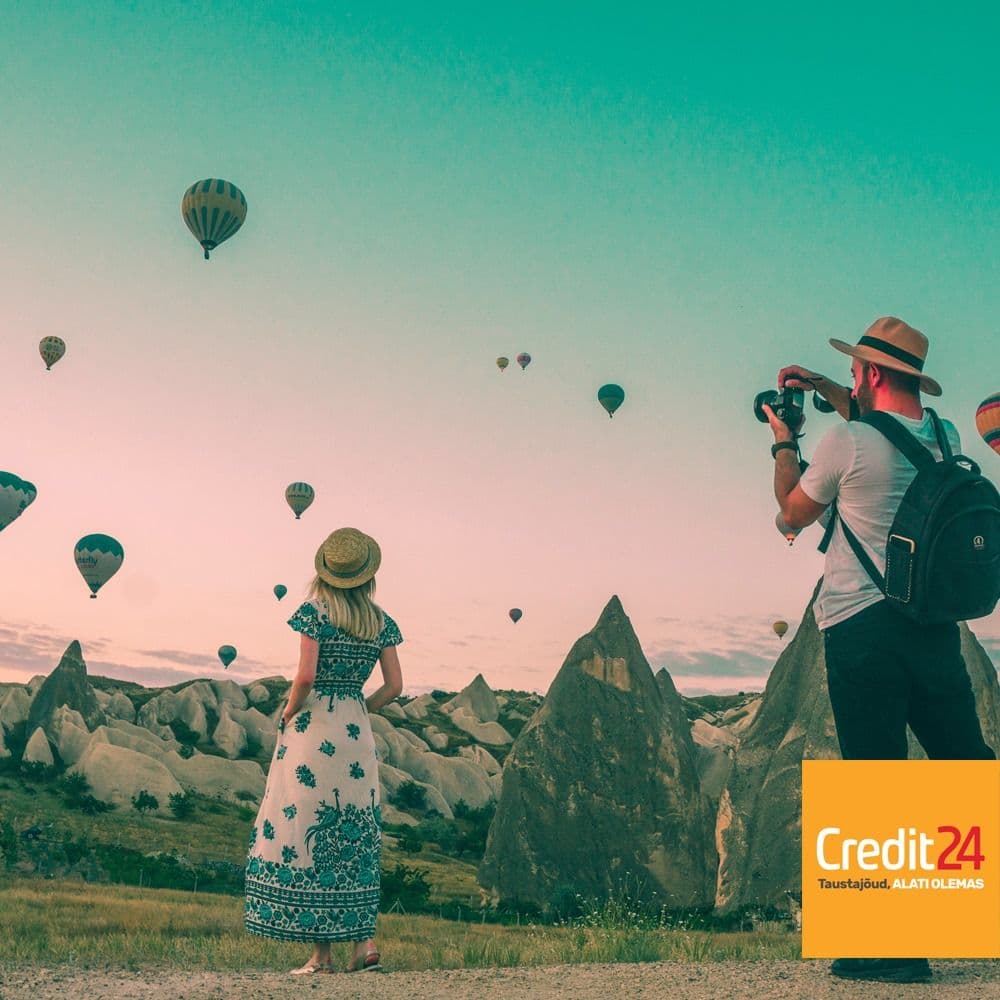 Kaks inimest vaatavad kuumaõhupalle kaljude taustal, paremal all "Credit24" logo.